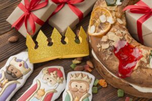 Imagen de roscon de reyes con una corona y figuritas de los Reyes Magos.