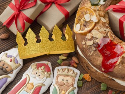 Imagen de roscon de reyes con una corona y figuritas de los Reyes Magos.